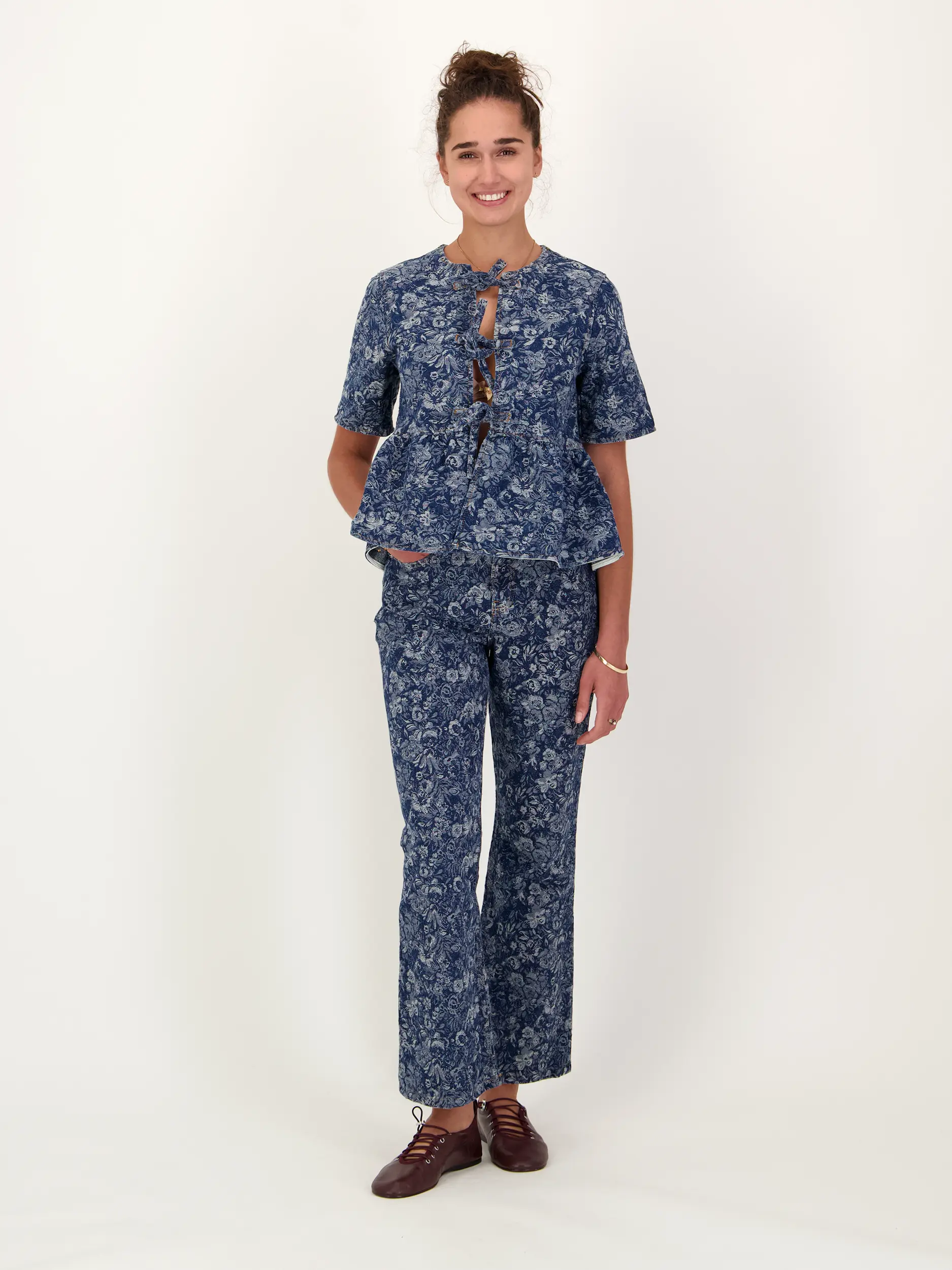 Jeansbluse mit Schleifen und Blumen Print kurzarm - Artikel Teil eines Outfits getragen von einem Modell - Farbe: Blau