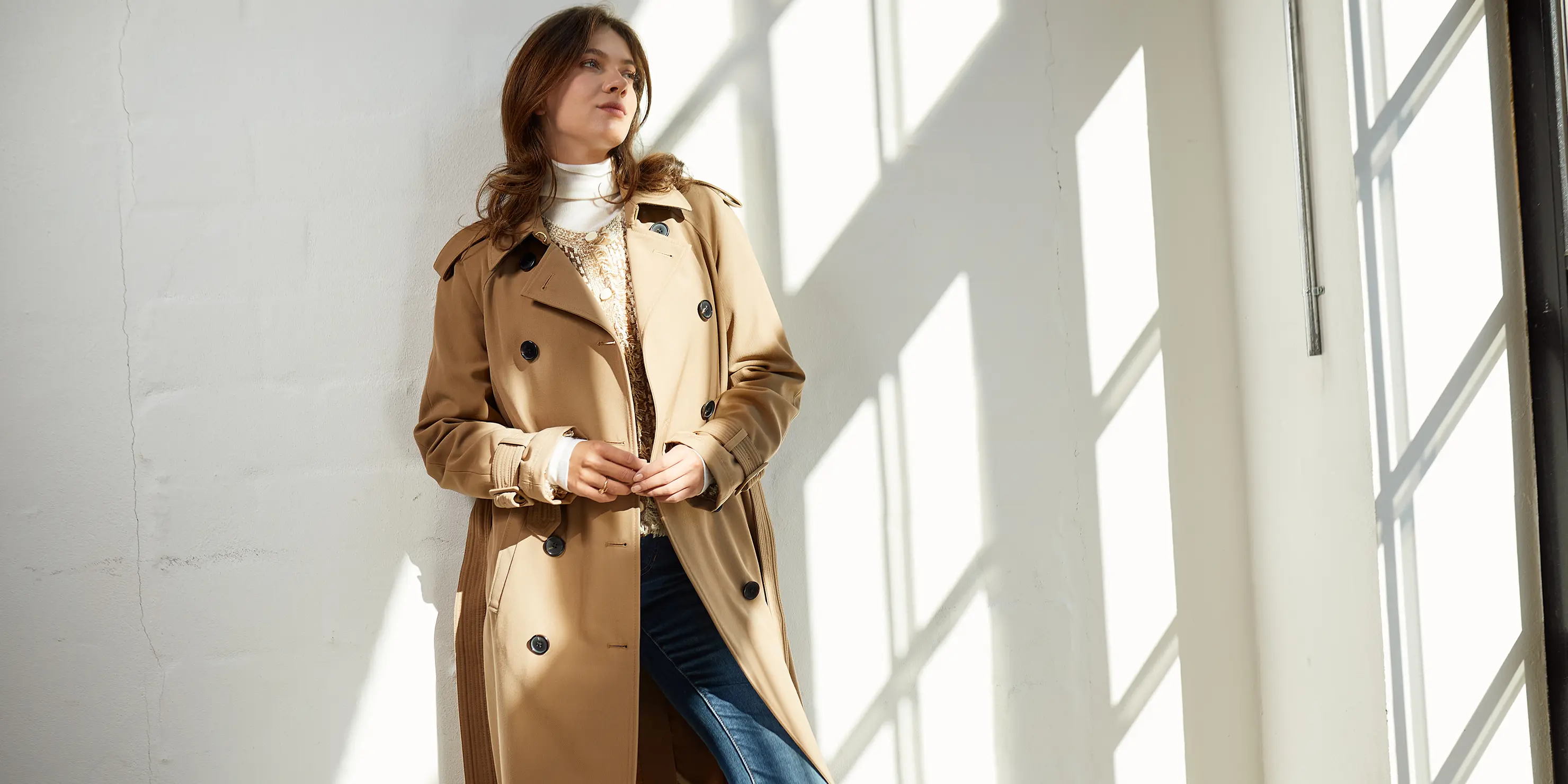 Das Bild zeigt eine Frau mit einem beigen Trenchcoat von Veronica Beard.  