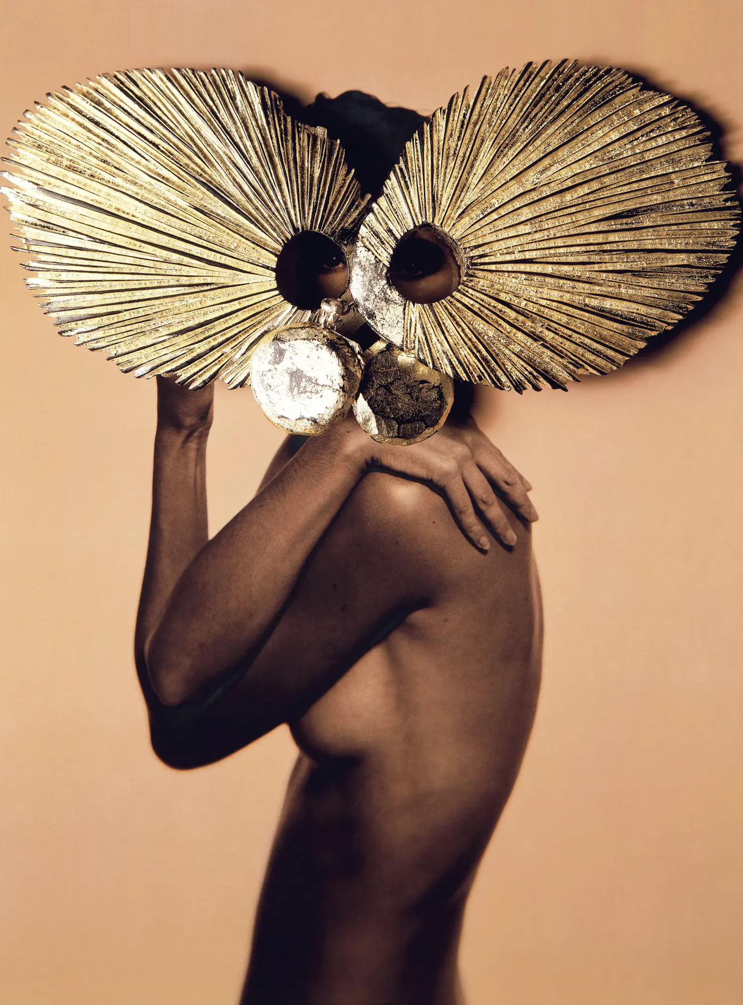 Das Bild zeigt eine nackte Frau mit einer goldenen Maske.