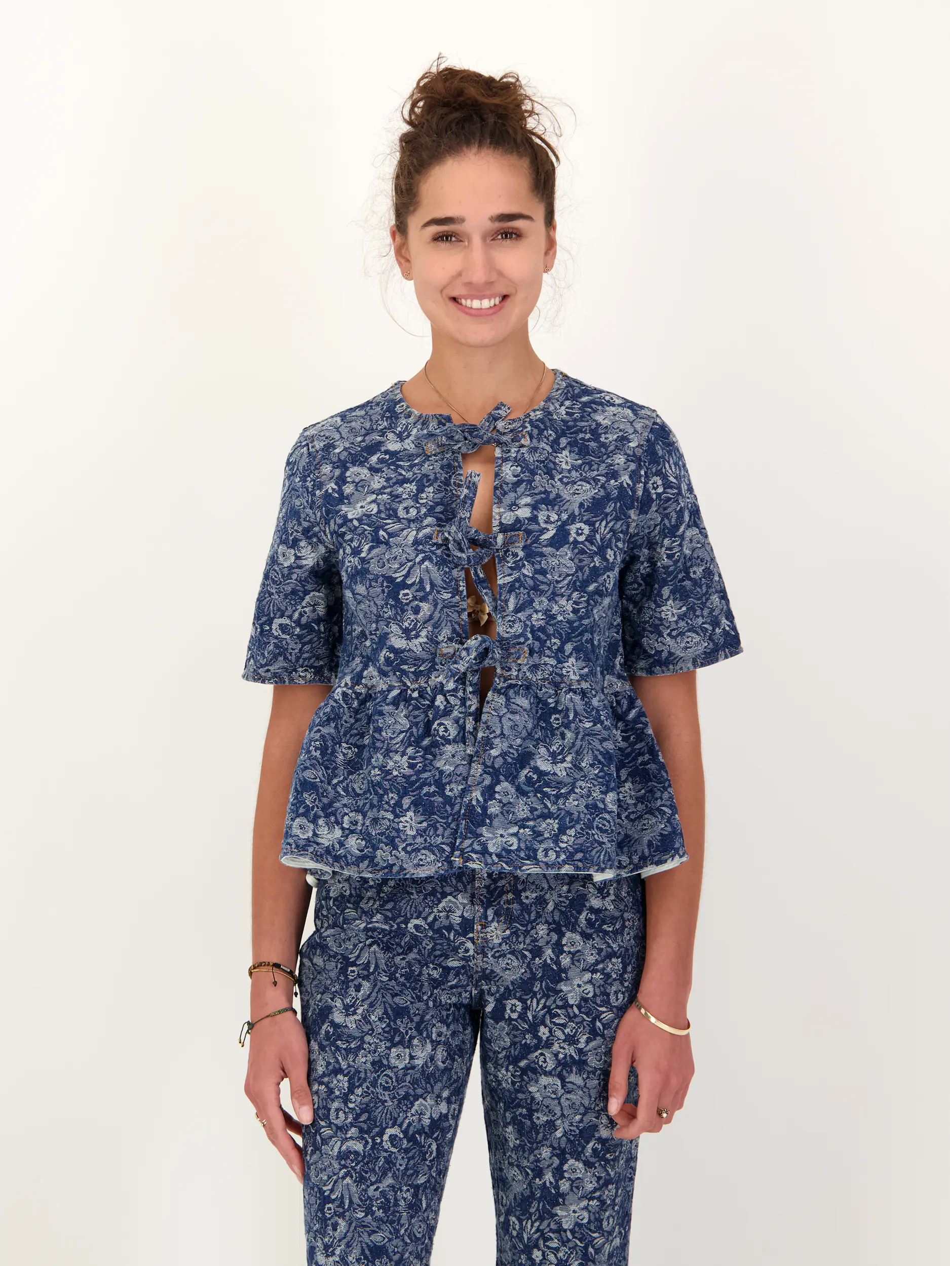 Jeansbluse mit Schleifen und Blumen Print kurzarm - Artikel Vorderseite getragen von einem Modell - Farbe: Blau